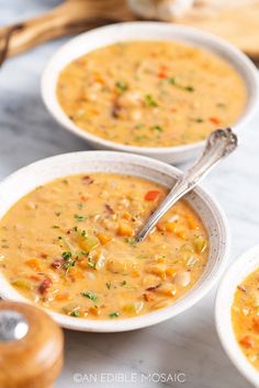 three bowls filled with soup sitting on top of a counter next to a wooden spoon