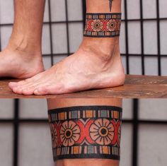 two people with tattoos on their legs and one has a cross tattooed on his leg