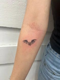 a small bat tattoo on the arm