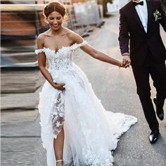 a bride and groom holding hands while walking down the street in their wedding gowns