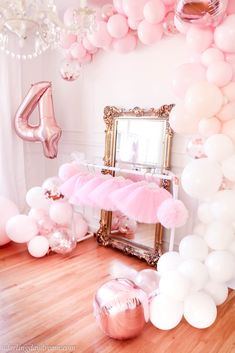 a room filled with balloons and pink furniture in front of a mirror on top of a hard wood floor