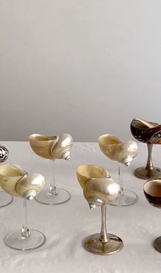 several wine glasses are lined up on a white tablecloth, with one empty glass in the middle