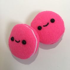 two pink balls with black eyes are sitting next to each other on a white surface