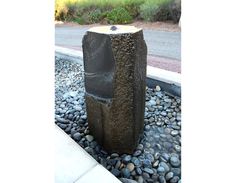 a stone fountain in the middle of a graveled area with rocks and stones around it