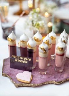 small desserts are arranged on a pink tray with gold trim around the edges and topped with meringue kisses