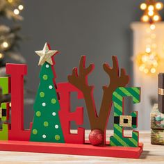 the word love spelled with wooden letters and christmas trees in front of a decorated tree