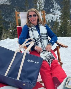 a woman sitting on top of a snow covered ground next to a bag and skis