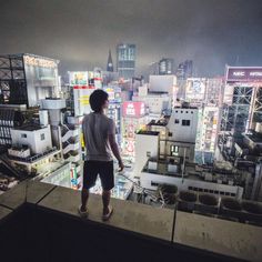 a man standing on top of a building looking down at the cityscape in the distance