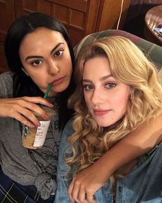 two women sitting next to each other with drinks in their hands and one holding a straw