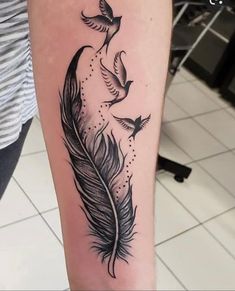 a black and white photo of a feather with birds flying around it on the arm