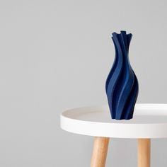 a blue vase sitting on top of a white table next to a wooden stick in front of it