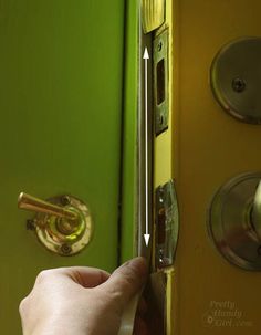 a person is opening the door with their hand and pointing it at the handle on the green door