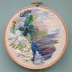 a close up of a embroidery on a wall hanging with beads and flowers in it