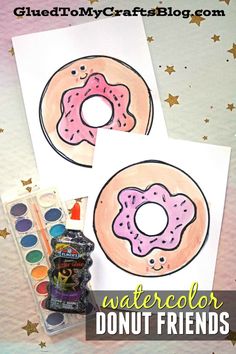 two doughnuts with pink icing and sprinkles on them next to watercolor paints