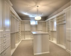 an empty walk - in closet with white cabinets and countertop space for the bar