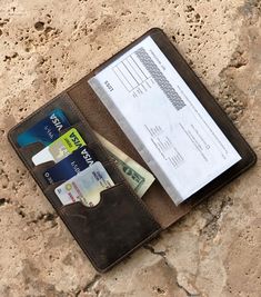 an open wallet sitting on top of a stone wall next to a paper and money