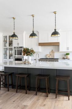 a kitchen with white cabinets and wooden stools in front of the island countertop