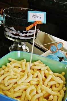 a blue bowl filled with lots of food on top of a counter next to a cake