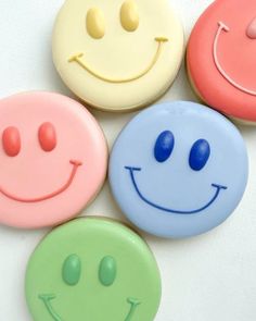 four different colored cookies with smiley faces on them