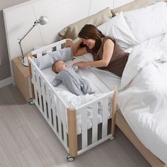 a woman laying in bed next to a baby sleeping on it's side,