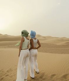 two women standing in the desert looking at the sand dunes with no one on them