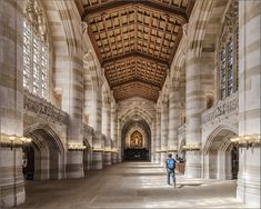 a man is standing in the middle of a large building with stone columns and arches