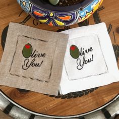 two napkins with embroidered designs on them sitting on a table