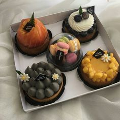 a box filled with different types of cakes on top of a white sheet covered bed