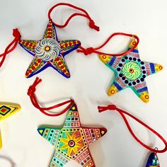 four colorful star ornaments hanging from red string