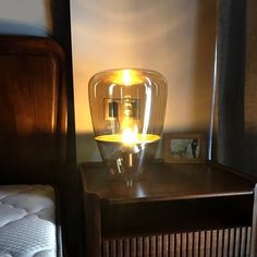 a glass vase sitting on top of a wooden table next to a night stand with pictures