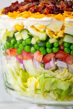 a layered salad with peas, cucumbers, bacon and lettuce in a glass dish