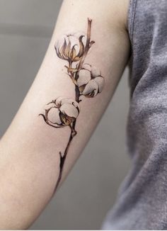 a woman with a tattoo on her arm holding a flower in one hand and a branch in the other