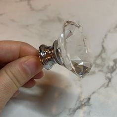 a person is holding a glass door knob on a marble counter top with white and gold accents