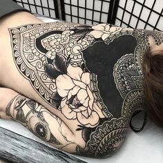 a woman laying on top of a bed covered in tattoos