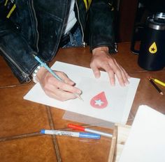 a person is drawing on paper with markers