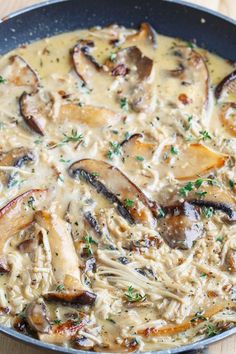 a skillet filled with chicken and mushrooms covered in gravy