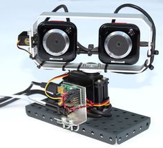 two cameras sitting on top of a piece of metal with wires attached to it and some wires