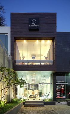 the front entrance of a modern building with stairs leading up to it's second story