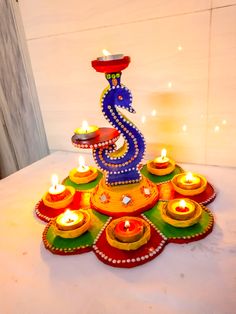 a colorful decorated diya with lit candles on the table in front of a white wall