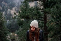 a young woman with long hair wearing a hat and looking down at her cell phone