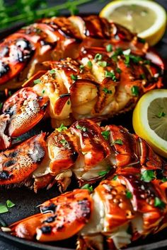 grilled lobsters with lemon wedges and parsley on a black platter