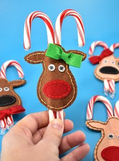 hand holding candy canes decorated with felt reindeer head and candy canes on blue background