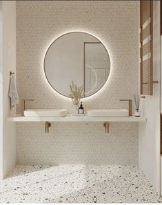 a bathroom with two sinks and a round mirror on the wall above it's counter