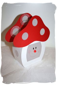 two red mushrooms sitting on top of a white box with polka dot dots in it