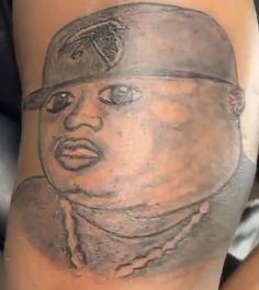 a close up of a person's leg with a tattoo on it that has a drawing of a man wearing a hat