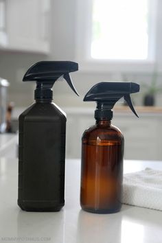 two spray bottles sitting on top of a counter next to each other, one brown and the other black