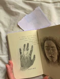 a person is holding an open book with drawings on it and paper next to them