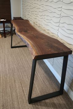 a wooden bench sitting on top of a carpeted floor next to a white wall