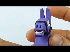 someone is holding a purple toy that looks like a cartoon character with eyes and ears