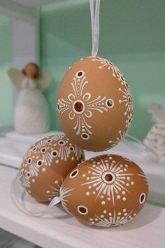 three brown eggs sitting on top of a white shelf next to angel figurines